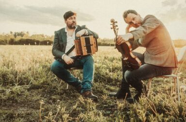 Spiers & Boden posing with their instruments on chairs in a field