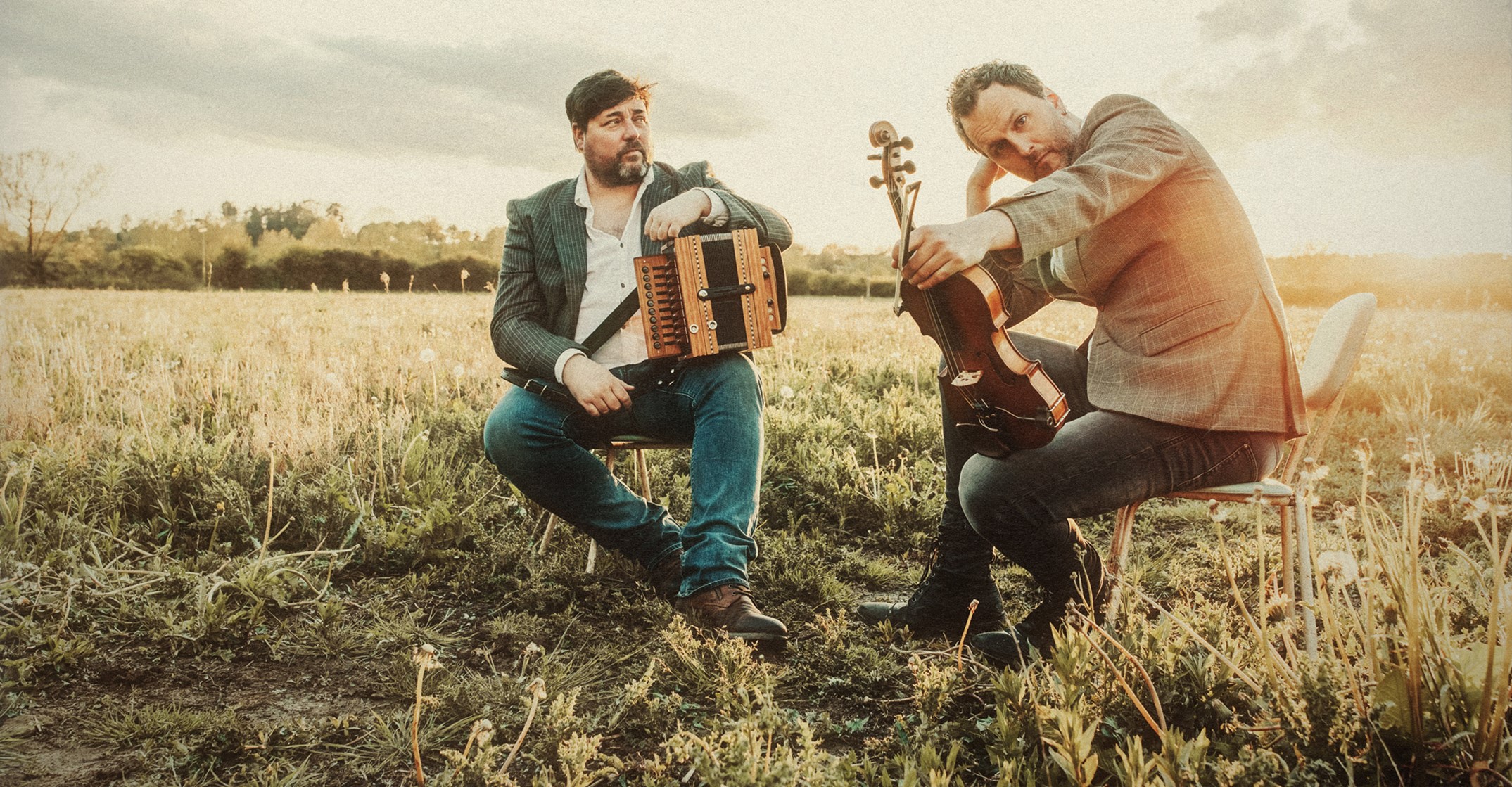 Spiers & Boden posing with their instruments on chairs in a field