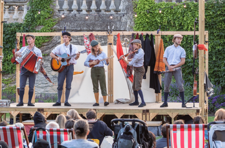 Five musicians on a small wooden stage outdoors